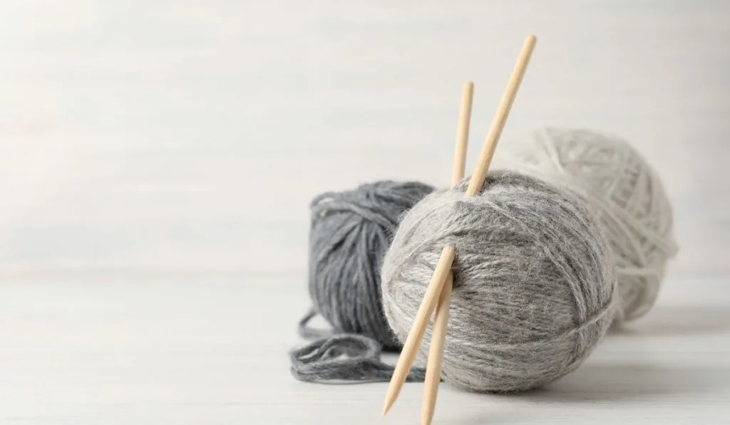 Balls of yarn with knitting needles on white background 