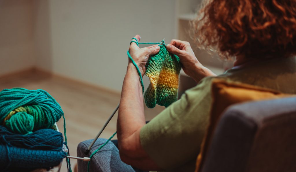 Close up of the hands of a senior woman knitting at home.
