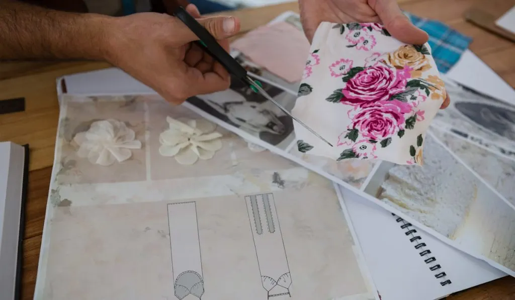 Cropped hands of designer cutting papers at table