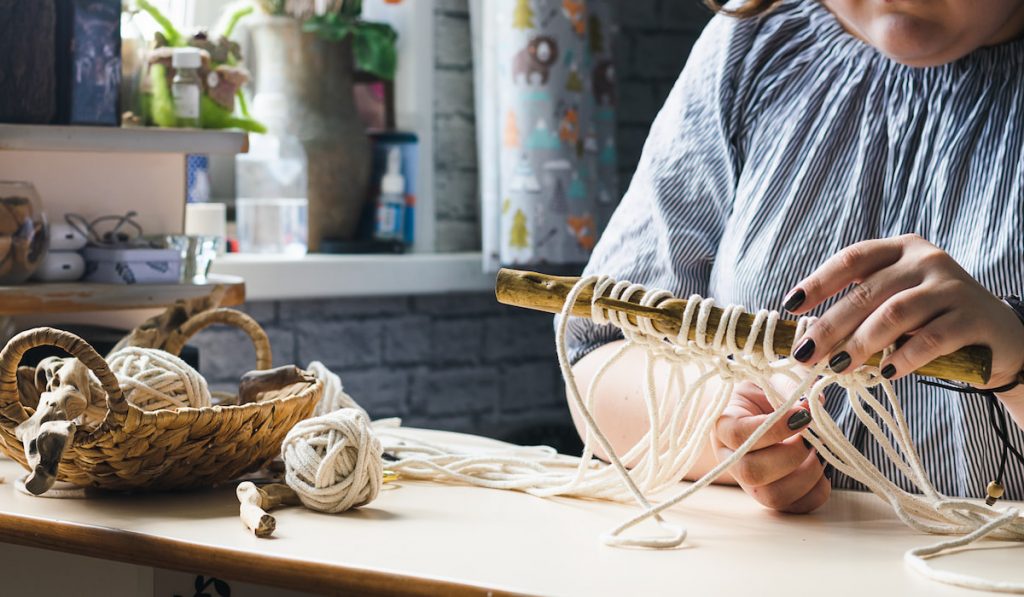 Female hands weave macrame home workshop