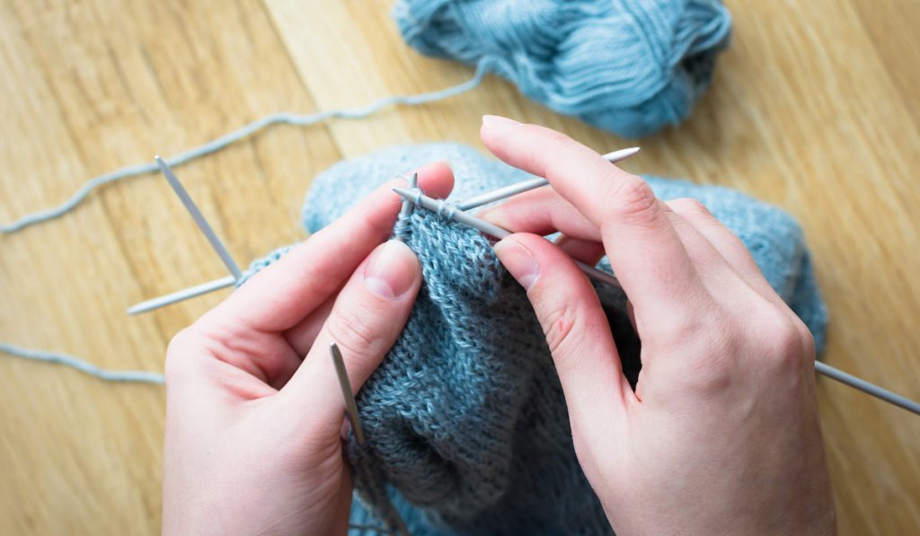 Knitting process using blue yarn on wooden table 