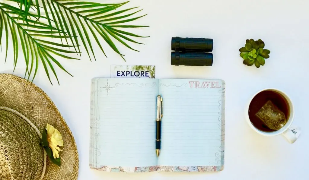 Open journal with blank pages in a travel flatlay