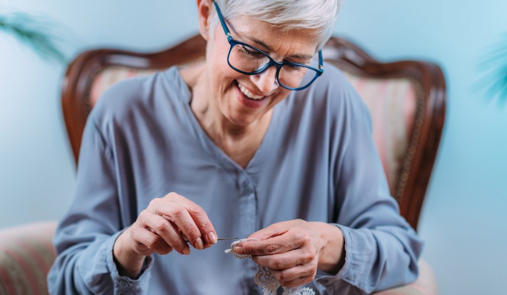 Smiling Senior Woman Doing Crocheting at Home 