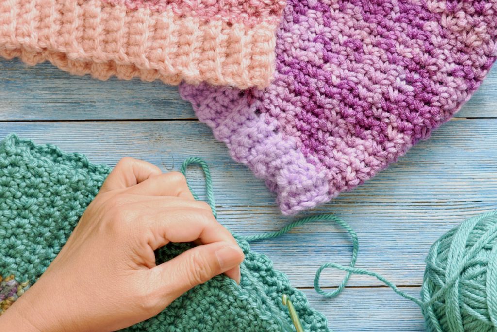 Woman crocheting beanies.

