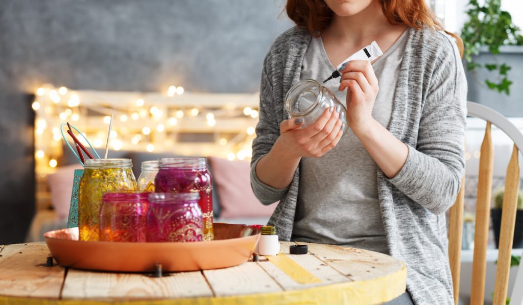 Woman decoupaging jar at home 