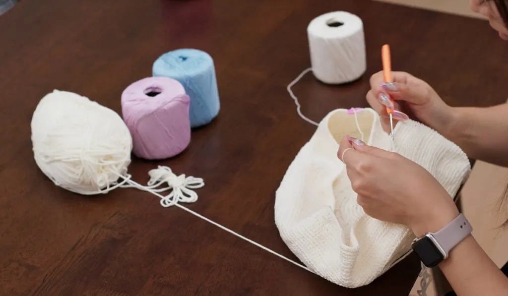 Woman hand knitting white yarn at home
