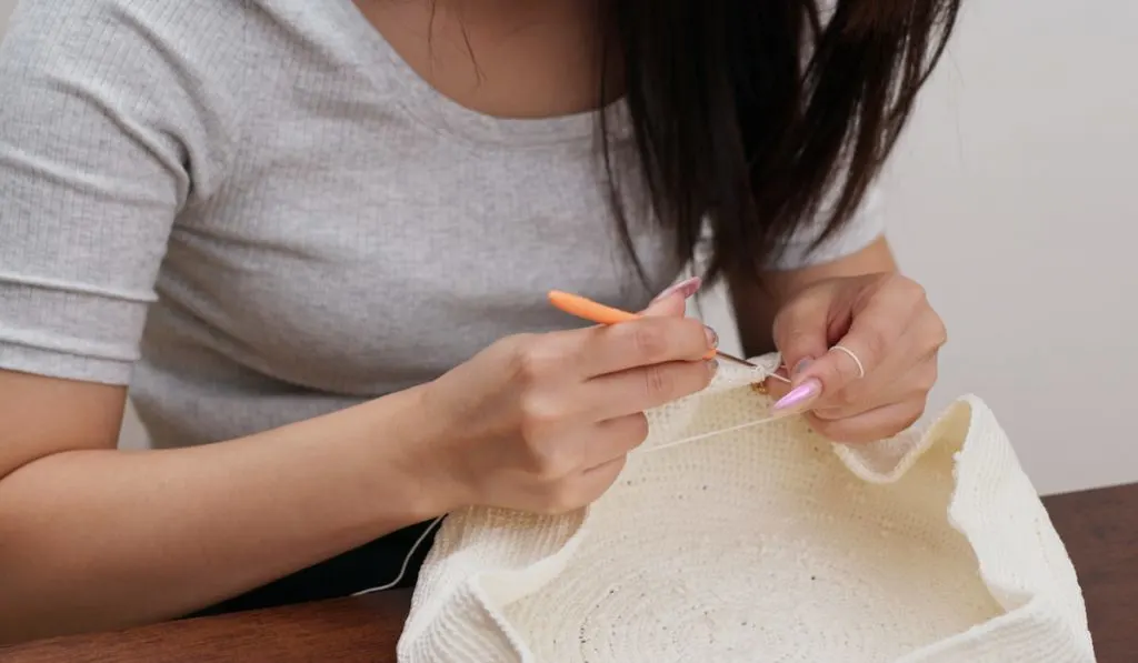 Woman using ergonomic hook crocheting at home 