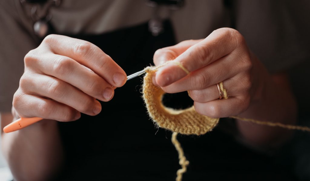Woman’s hands crocheting with a crochet hook.