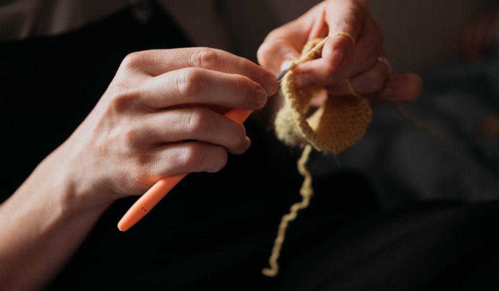 Woman’s hands crocheting with a crochet hook. 