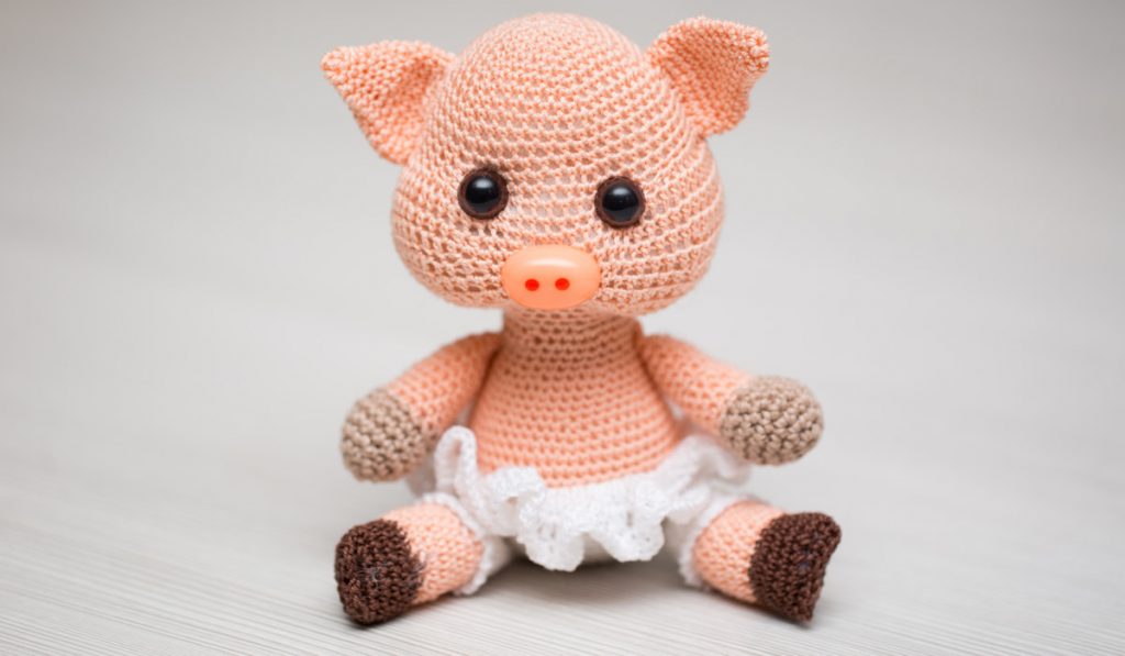 a crocheted pink pig toy on white background