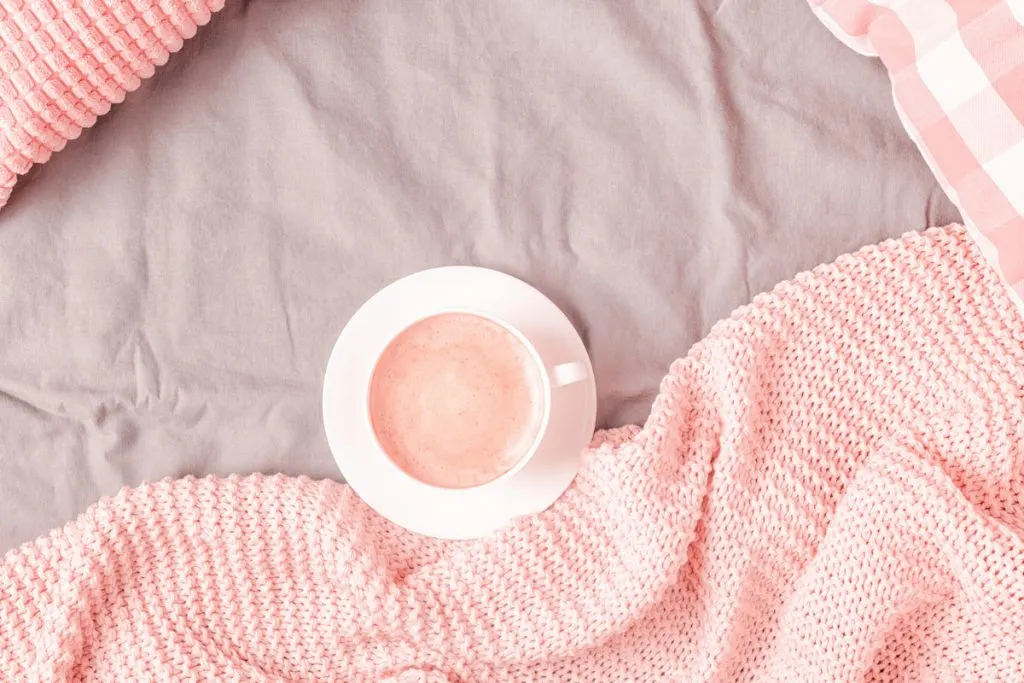 bed with pink knitted plaid blanket and coffee