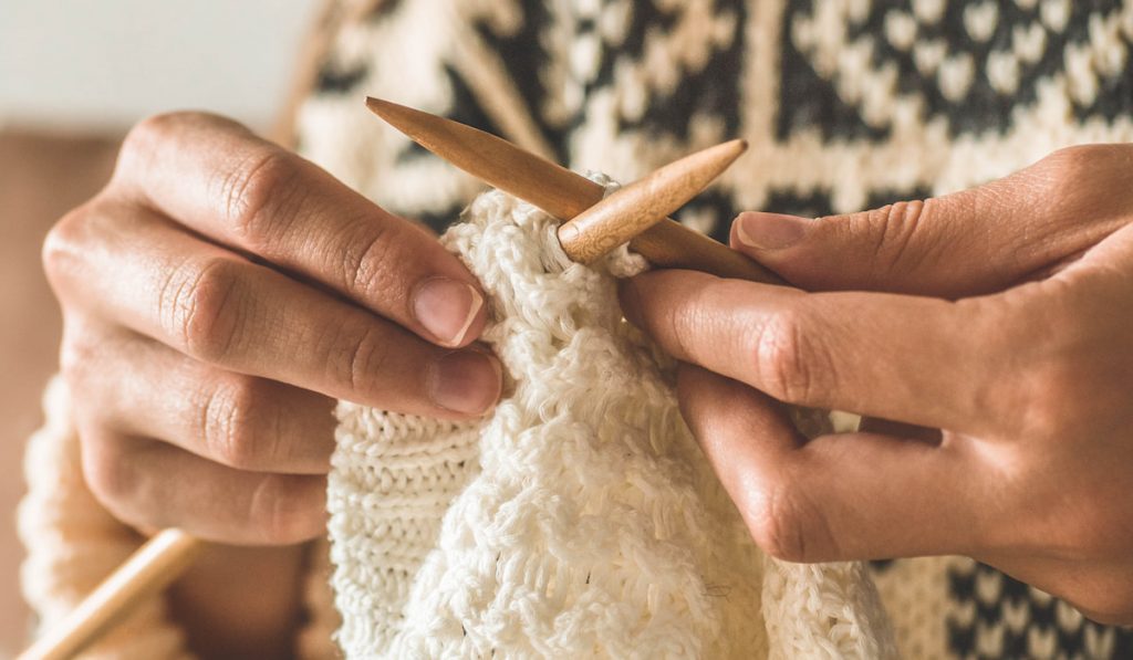 closeup of hand of woman knitting sweater