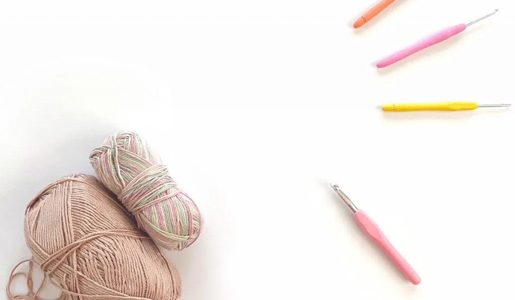 colorful crochet yarn and hooks on white background 