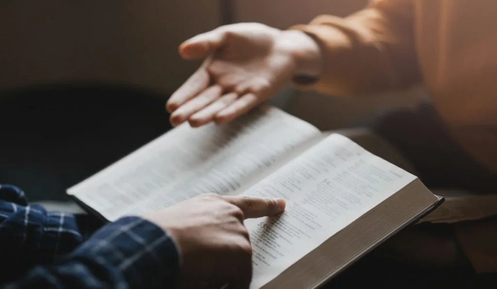 couple hands studying bible journal together