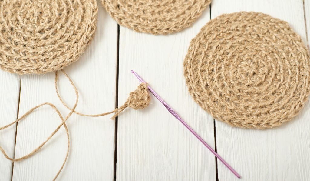 crocheting jute coasters and crochet hook on the table 
