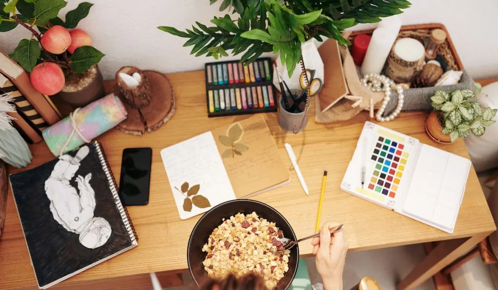 eating breakfast at desk with art supplies for art journal