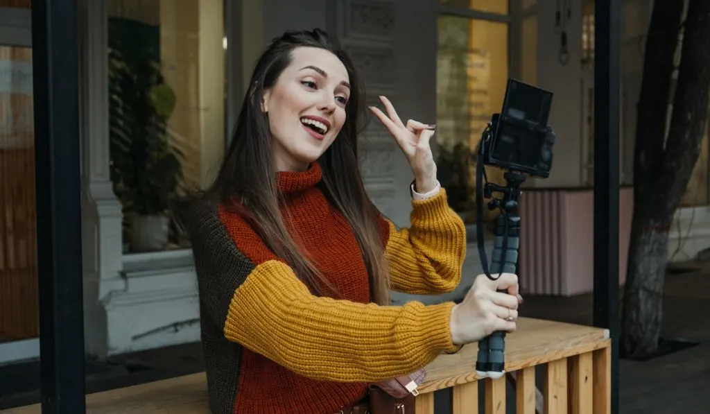 female content creator wearing knitted sweater filming herself 