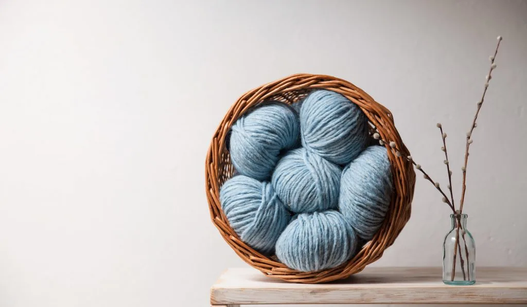 light blue yarn balls inside wooden basket on the table 