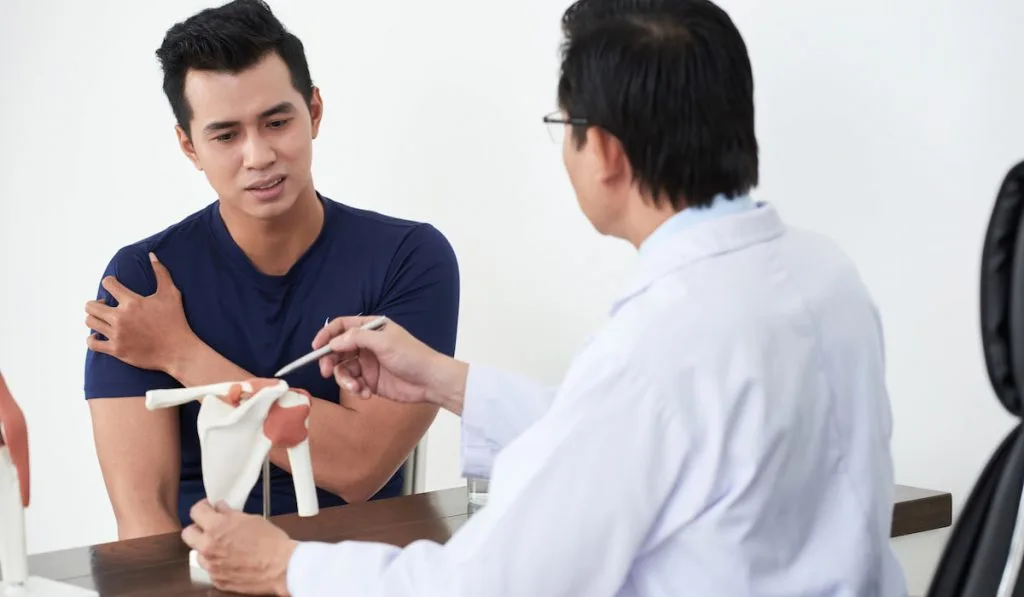 man and his doctor discussing about shoulder pain 