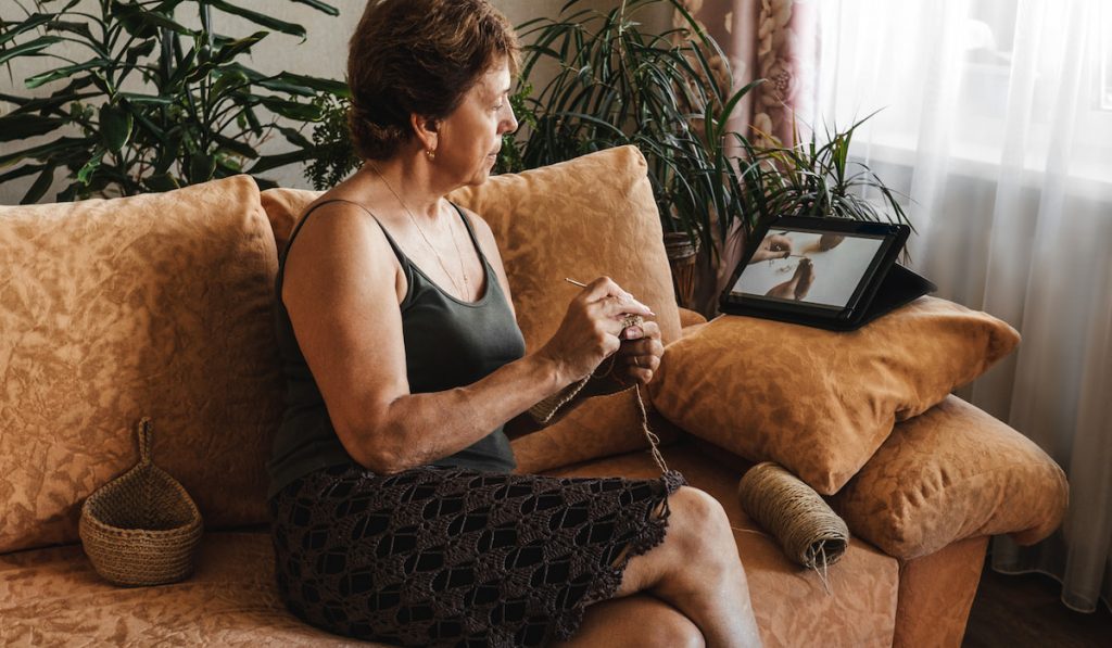 woman doing crochet by watching instruction via her iPad 
