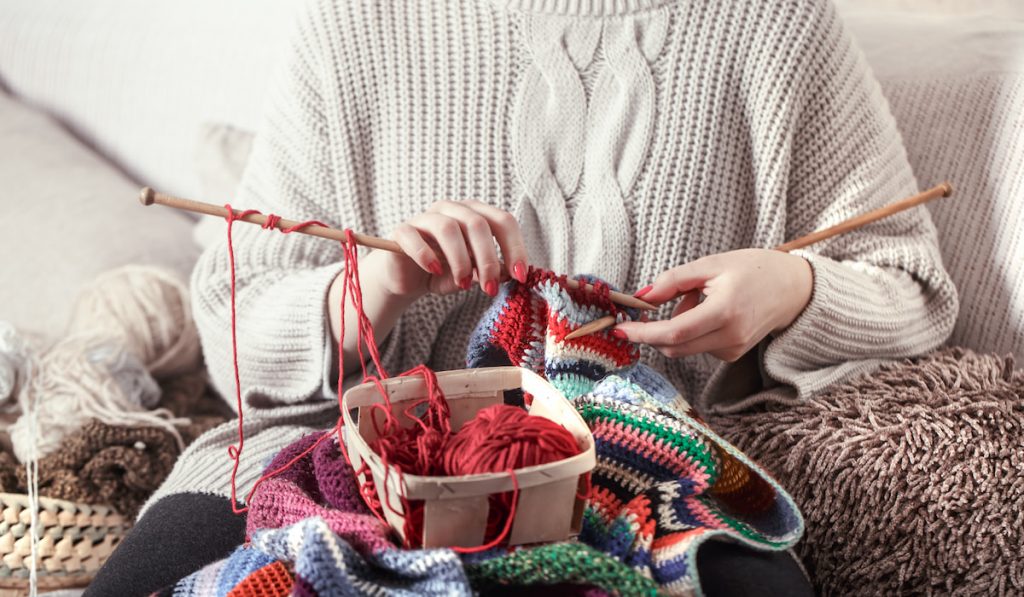woman knits knitting needles on the couch
