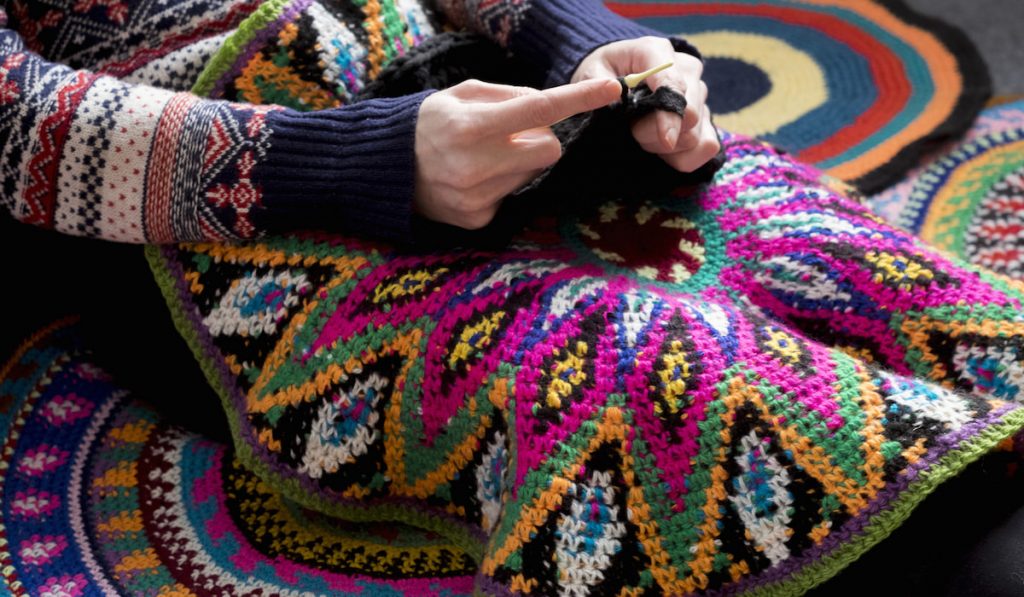 woman sitting on floor crocheting, surrounded by crochet circles