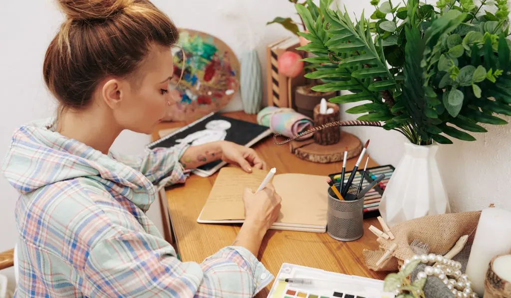 woman writing on her journal with different color of pens 