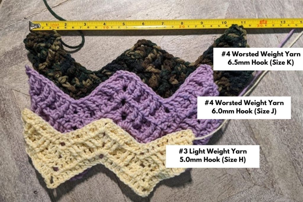 Three swatches of the double ripple crochet pattern stacked on top of each other. The top swatch is camouflage print yarn with a label that says "#4 worsted weight yarn; 6.5mm Hook (Size K)" This swatch measures 11 inches. The middle swatch is in purple yarn with a label that says "#4 Worsted Weight Yarn; 6.0mm Hook (Size J)". This swatch measures about 9.5 inches. The final swatch is in yellow yarn with a label that says "#3 Light Weight Yarn; 5.0mm Hook (Size H)" and the swatch measures approximately 8.5 inches. There is a measuring tape at the top of the image.