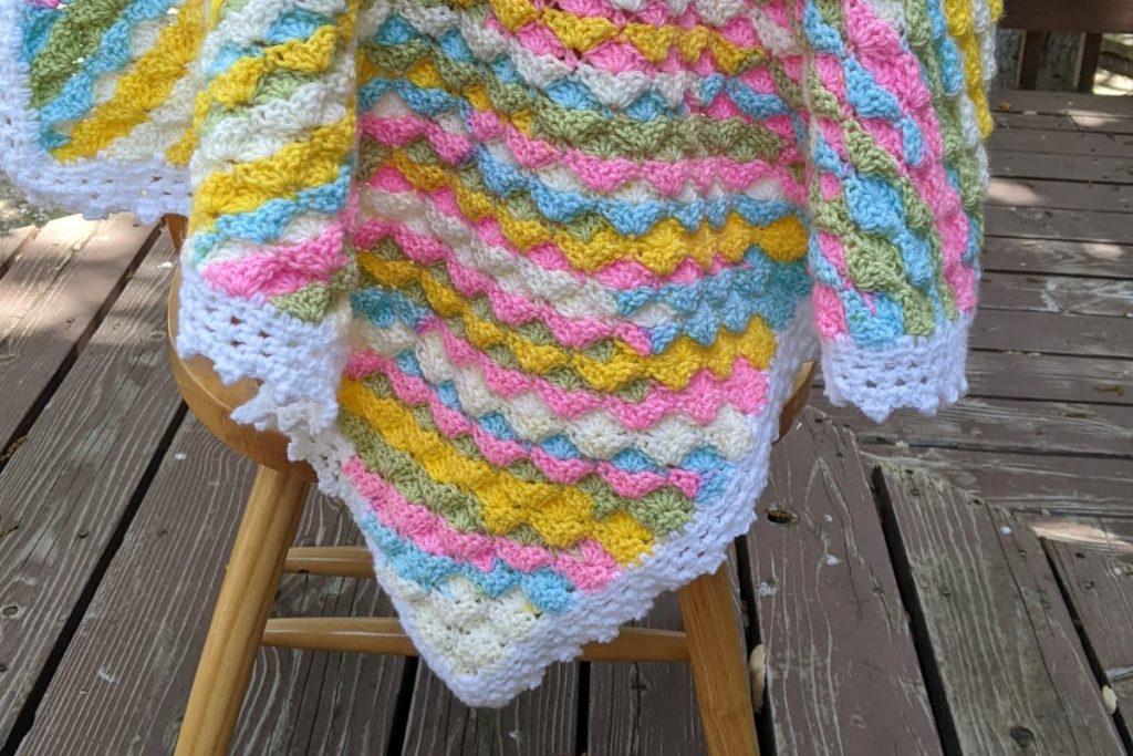 finished crochet corner to corner shell stitch hanging on a wooden chair