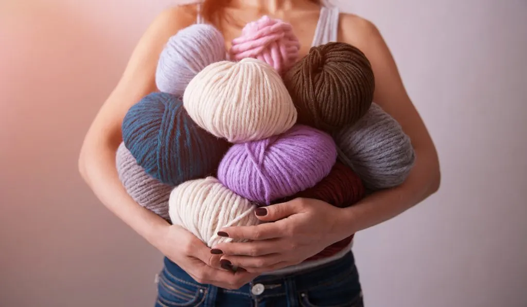 young woman carrying a bunch of different colored yarn balls