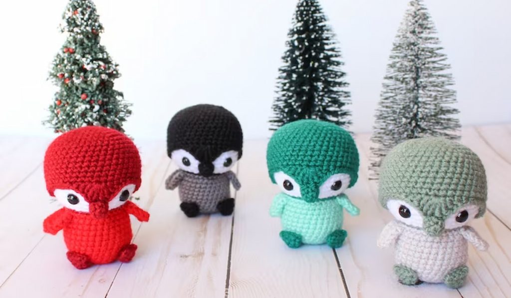 Baby Penguin Amigurumi by StorylandAmis with small trees in the background 
