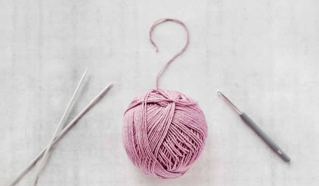 Ball of yarn, crochet hook and knitting needles spokes