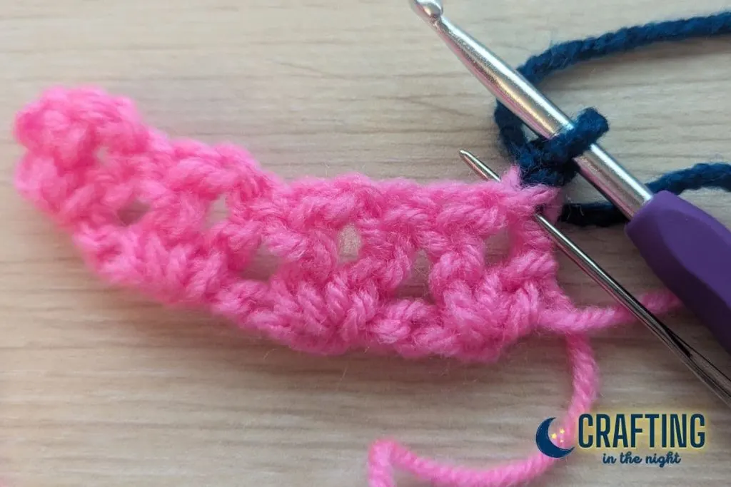 a crochet swatch with a yarn needle placed through the first double crochet indicating where the next stitch should go