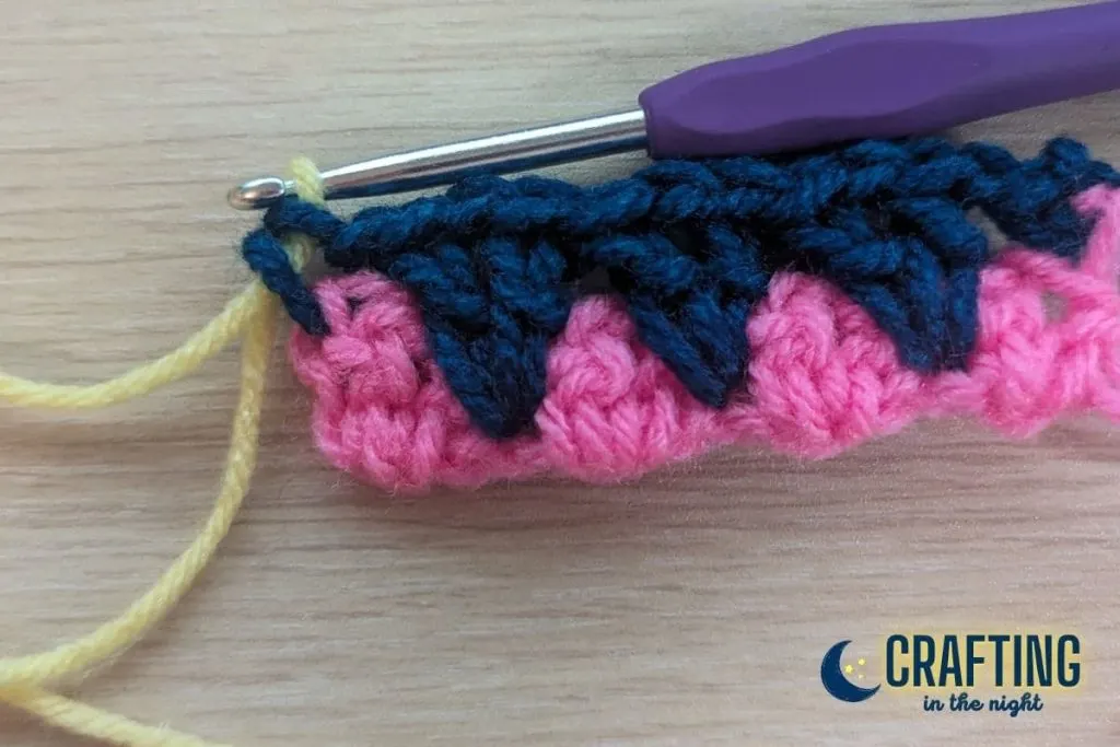 a crochet swatch showing a change of color from navy to yellow