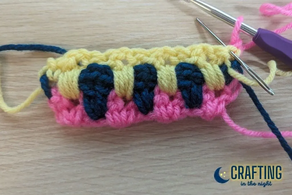A yarn needle shows where the next stitch of the crochet pattern should be placed.