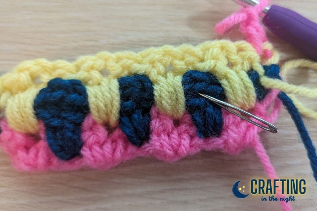 a yarn needle shows where the next stitch should be placed in a crochet swatch