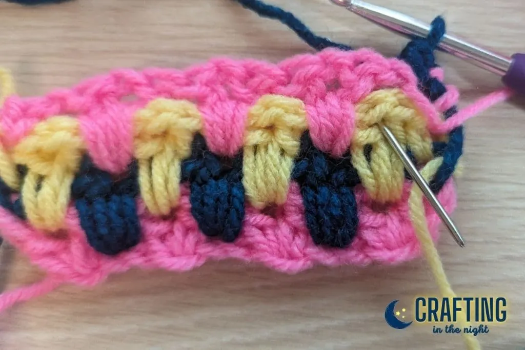 a yarn needle shows where the next v-stitch in the crochet swatch should be placed.
