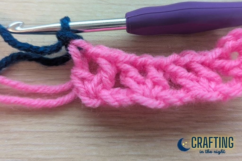 A crochet swatch showing a chain 1 with navy yarn