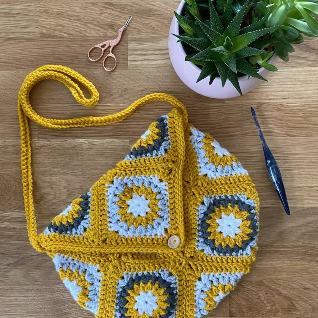 StarBurst Four Way Granny Square Tote Bag Crochet Pattern and a potted plant on the table
