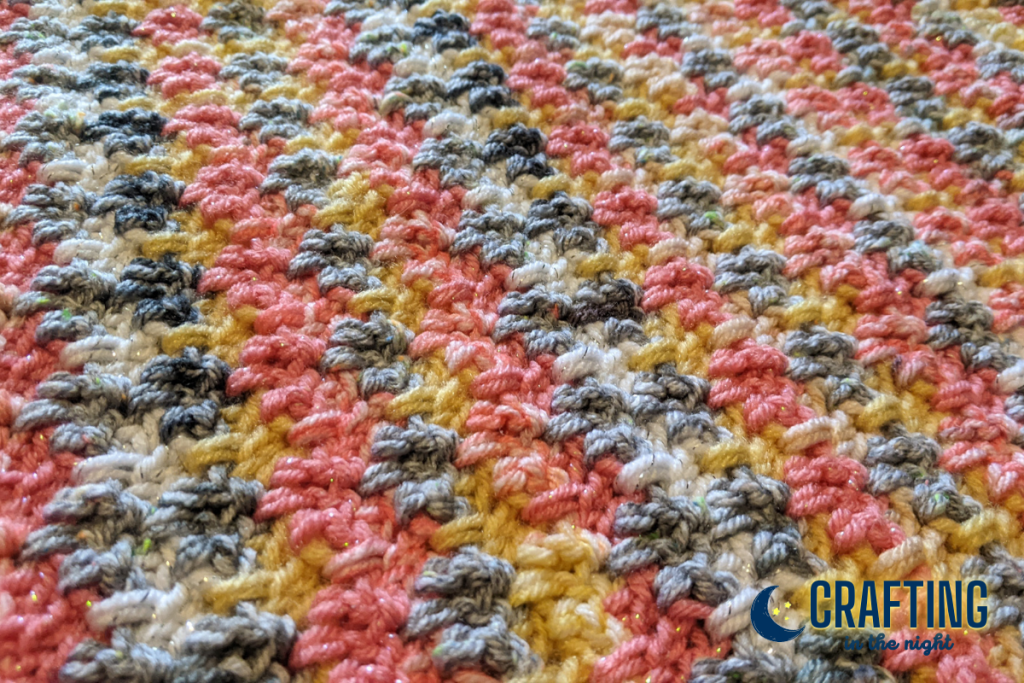 extreme closeup detail of the stitch pattern and repeating color sequence of the sunset serenity crochet afghan