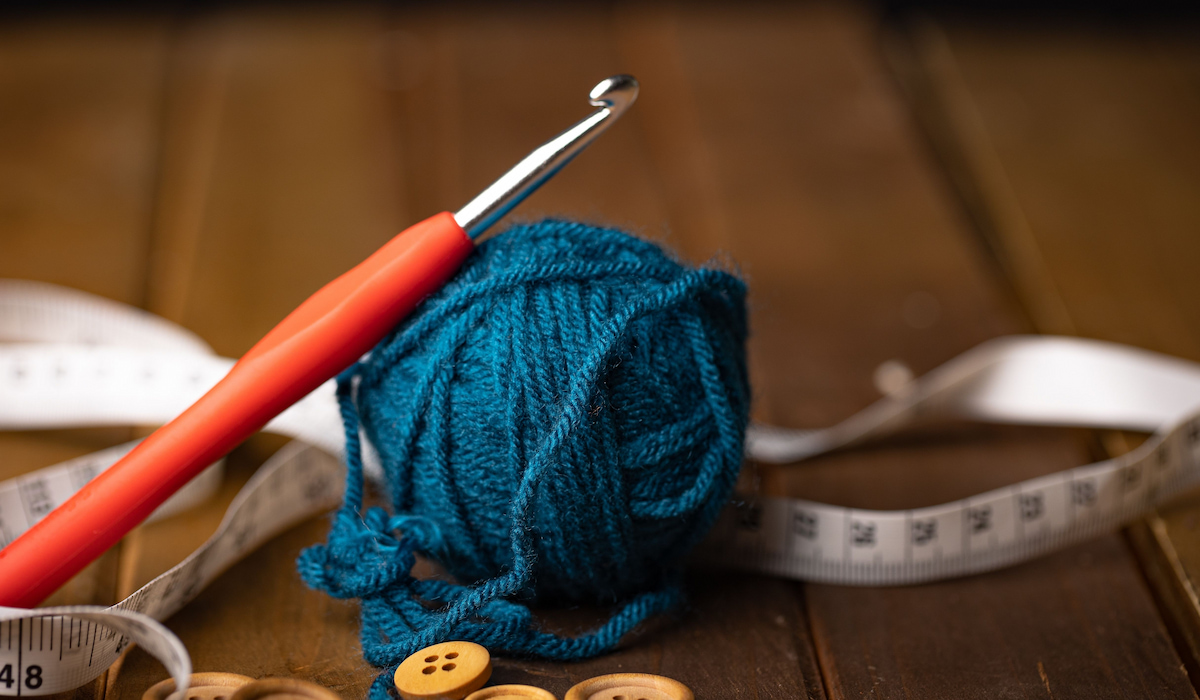 https://craftinginthenight.com/wp-content/uploads/2023/08/an-ergonomic-crochet-hook-leaning-on-top-of-a-blue-yarn-ball-ss230830.jpg