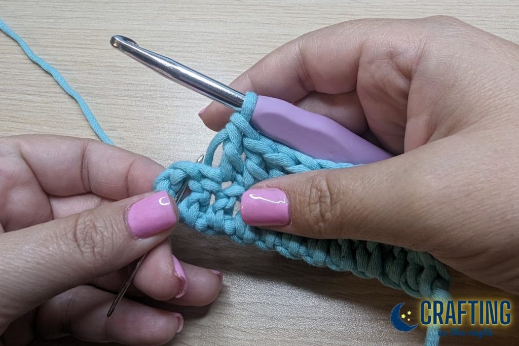 Continue working double crochets all the way across the row. In this photo I have one regular double crochet left and the yarn needle is showing the top of the turning chain from the row below where my last stitch needs to be placed.
