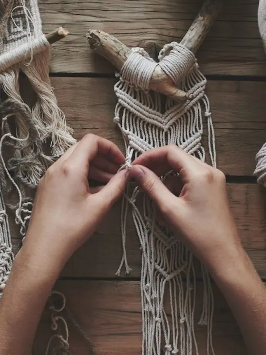 hands doing macrame on rustic wooden table