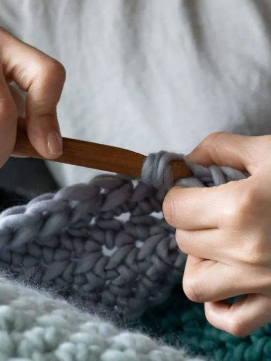 woman doing crochet using a wooden hook