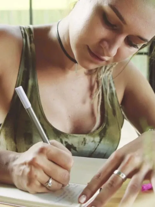 a beautiful girl writing her thoughts on a journal