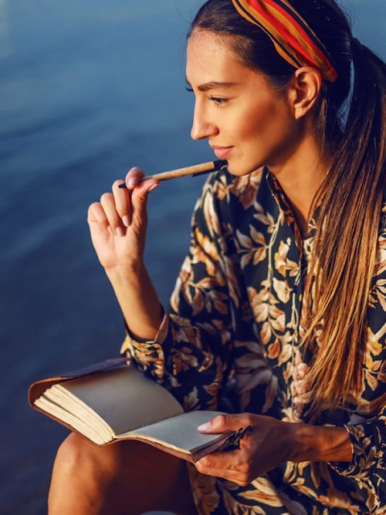 a beautiful woman near a lake thinking of what to write