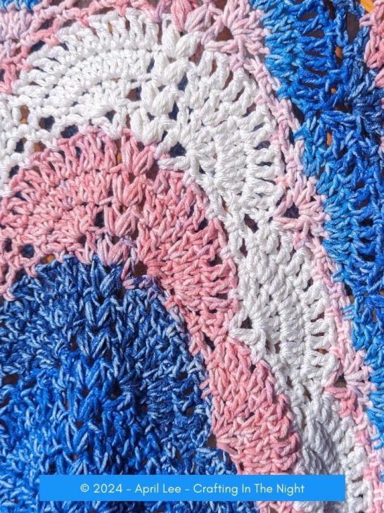 Close up shot of Blue with pink Flora Blossom Crochet Blanket draped on the chair