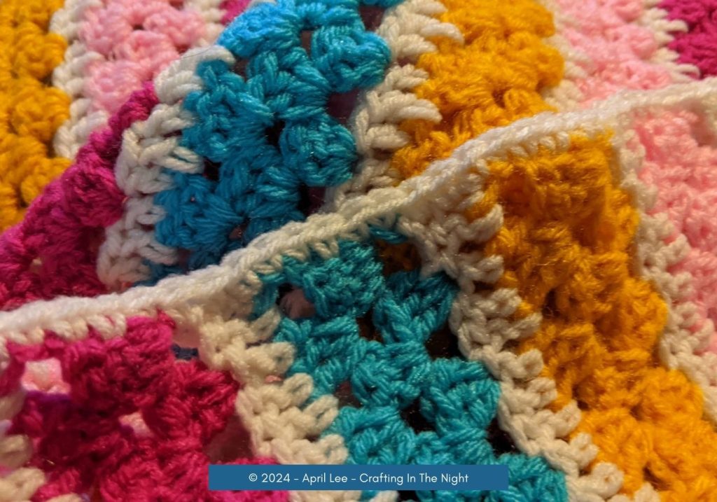 Close-up view of Modern Granny Stripe Blanket pink and blue spread out on the ground