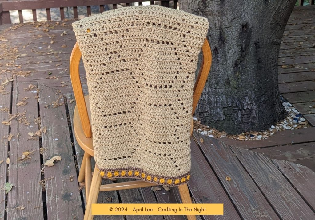 honeycomb crochet blanket hanging on a chair at the deck